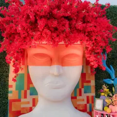 Art and nature collide in this striking installation featuring a stoic head sculpture crowned with a vibrant explosion of red bougainvillea. This piece exemplifies my approach of using unexpected combinations to create memorable focal points.