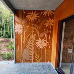 A full shot of the earthy tropical mural, showing how the tones of the painting harmonize with the natural stone flooring and wooden door frames.