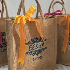 A bespoke jute giveaway bag, personalized with the name 'Eesha' and the event date. We offer detailed customization for weddings, making your favors truly unique.