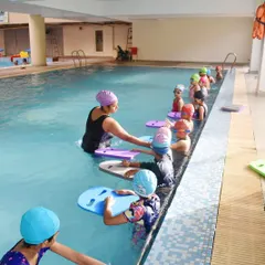 I believe in hands-on coaching, especially for young beginners. Here, our female coach guides kids through their first kicking exercises with kickboards in our Gurgaon pool.