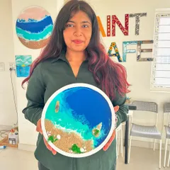 A guest proudly holds up her finished beach resin art. The way the resin creates natural-looking waves is truly magical, and it's a process anyone can learn.