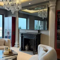 After: The same living room transformed into a luxurious space, featuring a classic black marble fireplace, elegant sofas, and a large mirror that amplifies the light and space.