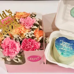 A heart-shaped bento cake with a hand-painted ocean theme for Mother's Day. This is paired with a 'World's Best Mom' flower arrangement, showing our custom art capabilities.