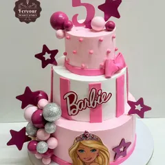 A grand three-tier Barbie cake for a 5th birthday party. This design combines stripes, polka dots, and character images with a cascade of pink and silver decorative balls for a fun and glamorous look.