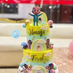 A cheerful and colorful two-tier Cocomelon cake, perfect for a first birthday. This tall cake features the beloved characters, rainbows, and a vibrant color palette, bringing the popular nursery rhyme show to life.