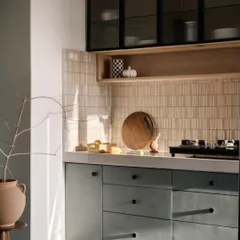 We gave this kitchen a modern-retro vibe with bold checkered flooring. The muted green cabinets are paired with a textured tile backsplash and black-framed glass overhead units, creating a space with lots of personality and warmth.