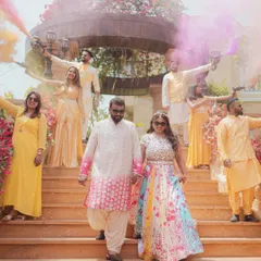 A fun-filled moment at a pastel-themed Haldi, with the couple and their friends celebrating with colorful smoke bombs.
