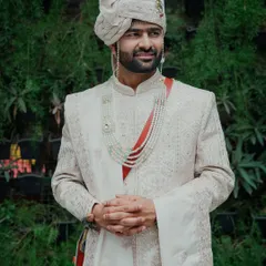 This portrait showcases the groom in his elegant off-white sherwani and traditional Pheta. The natural, outdoor setting provides a beautiful backdrop for this timeless shot.