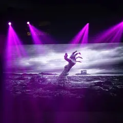 We use lighting and visuals to enhance the theme. This is an LED screen displaying a spooky image, with purple spotlights adding to the eerie ambiance of the Halloween party.