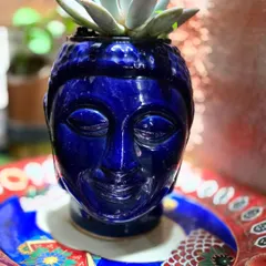 A ceramic Buddha-head planter painted a brilliant blue. Our pottery painting sessions allow you to add your personal touch to pre-made ceramic items, creating unique decor for your home.
