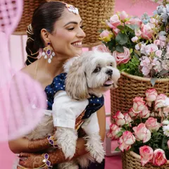 The most important guest of honor! A heartwarming shot of the bride holding her beautifully dressed-up dog amidst the vibrant decor of her Mehendi ceremony.