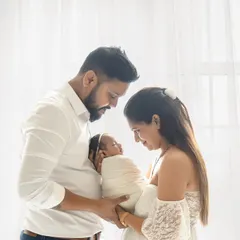 A beautiful, light-filled portrait of new parents adoring their swaddled baby. Capturing this profound connection is a key part of my newborn family photoshoots, creating a memory you will treasure forever.