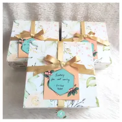 A set of "Sorry" gift boxes with a lovely floral pattern and gold ribbons. The thoughtful packaging and personalized tag help convey genuine sentiments and show you care, even when you can't be there in person.