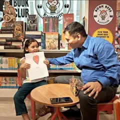 A daughter proudly shows her Father's Day drawing to her dad. We love being the place where families can connect and create sweet memories together.