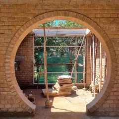 A circular archway being constructed with stabilized earth blocks at the 'FM-177' site. This feature frames the view and creates a beautiful play of light and shadow.