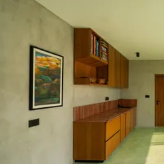 A vibrant green oxide floor flows through this space, complemented by custom wooden cabinetry. The contrast between the smooth, colorful floor and the warm grain of the wood creates a unique and energetic interior.