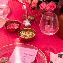 A close-up of a vibrant pink tablescape. Every element, from the charger plates and welcome notes to the small bowls of fresh petals, is carefully chosen to match the theme.