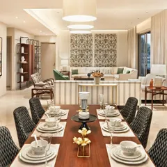An open-plan design connects the dining and living areas, creating a sense of spaciousness and flow. We used a consistent palette of warm woods and neutral fabrics, with patterned dining chairs adding a layer of visual interest to this modern Indian home.