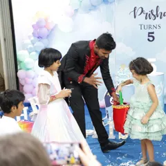 I make sure the kids are the stars of the show. Here, I'm getting some help from two young audience members for a classic "magic bag" illusion at a 5th birthday party. It's all about participation and laughter.
