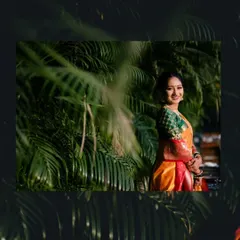 A beautiful bridal portrait of the bride smiling, framed by lush green foliage that makes her colorful saree pop.