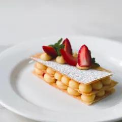 A classic strawberry mille-feuille, with layers of crisp puff pastry, light crème pâtissière, and fresh Mahabaleshwar strawberries. This dessert is a seasonal special, celebrating the best of the winter harvest.