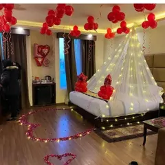 I created this romantic room setting with red balloons, a heart made of artificial rose petals on the floor, and a bed canopy illuminated with warm fairy lights. It's a classic setup for an anniversary or special surprise.