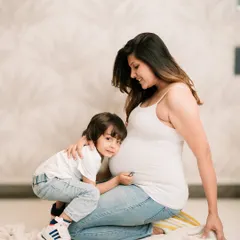 A soon-to-be big brother listens to his mommy's belly, a sweet and classic maternity pose.