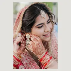 A candid moment of the bride adjusting her earring, her hands adorned with beautiful mehndi. We love capturing these small, natural gestures that happen while getting ready.