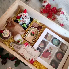 This is what my fully curated Christmas hamper looks like. It's a treasure box of my best festive bakes, including a mini bento cake, a chocolate bar, assorted cakesicles, macarons, and hot chocolate bombs, all packed beautifully in a wooden crate.