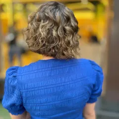 The back view of a curly bob with beautiful highlights. This style shows that short, curly hair can be the perfect canvas for creative and dimensional color.