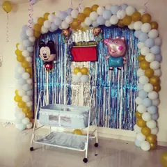 For a more playful naming ceremony, I can incorporate cartoon themes. This decoration features a balloon arch and cutouts of Mickey Mouse and Peppa Pig alongside the decorated cradle.
