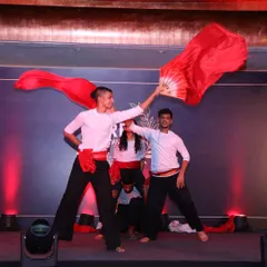 Our dancers use props like these vibrant red fans to add color and movement to the performance. This shot captures the energy and artistry of our Indian fusion choreography during a corporate showcase.