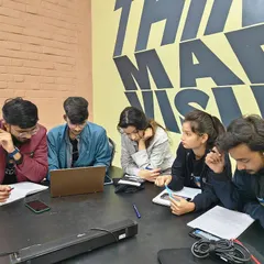 A small group of students collaborating around a laptop. Peer-to-peer learning is a vital part of my workshops, as it mirrors the teamwork required in a professional design studio.