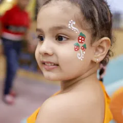 A close-up of some beautiful face paint art. Our talented artists can create a wide variety of designs, from simple strawberries to intricate patterns, to add a touch of magic to any child's look.