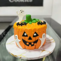 A spooky jack-o'-lantern cake for a Halloween party. This design features a dripping effect and is adorned with fondant ghosts and bats.