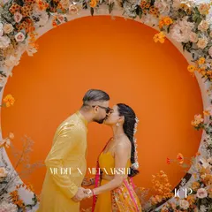 A romantic kiss in front of a stunning floral backdrop at a Haldi ceremony in Thailand.