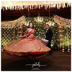 The bride and groom take center stage, their joy illuminating the elegant reception decor. The bride's twirling lehenga adds a beautiful sense of motion to the scene.