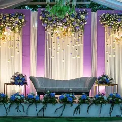 We created this dreamy reception stage with hanging floral chandeliers and soft purple and blue lighting. The cascading flowers and elegant seating make it a truly magical setting for an evening event.