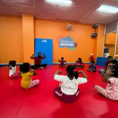 An instructor leads a group of children in a fun warm-up exercise. Mimicking the teacher helps with focus and body awareness, all while getting ready for more action.