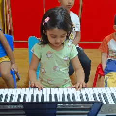 A young student at our summer camp, fully focused on playing her first notes. We provide individual attention even in a group setting to ensure every child learns correctly.