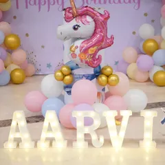 Personalized details make a party special. This setup includes light-up letters spelling the birthday girl's name, 'AARVI', as part of the Unicorn theme.