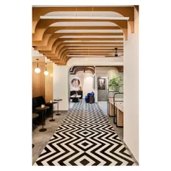 The central corridor features a striking black and white tiled floor that resembles a carpet, leading the eye through the space. The arched ceiling fins and informal seating nooks create a warm and inviting pathway.