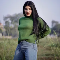 An outdoor fashion shoot in a natural setting. The contrast between the green field and the model's sweater creates a vibrant, eye-catching portrait.