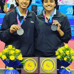 Kushi V and her partner proudly display their silver medals from the 36th National Games in Gujarat. This achievement in the Women's Doubles category is a highlight of her competitive career.