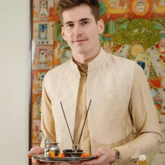 A festive moment, ready for a pooja. This beige vest with subtle embroidery, paired with a matching kurta, is a perfect ensemble for traditional ceremonies and family celebrations.