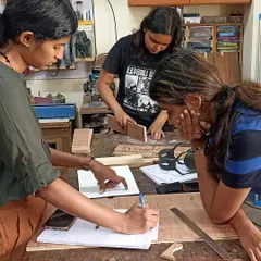 Design students collaborating on a project, sketching out ideas and planning their cuts. This is where theory meets practice.