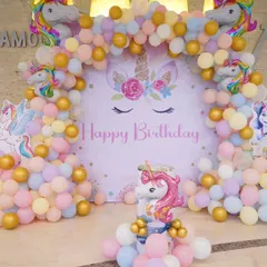 A detailed look at the Unicorn birthday backdrop, complete with a beautiful balloon arch in pastel shades and gold, and multiple unicorn figures.