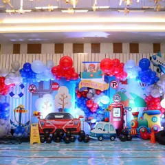 For Luv and Kussh's birthday, we created a world of travel. This main backdrop combined land, air, and sea transport themes with a Ferrari cutout, a gas station, a train, and an airplane, making it a grand stage for their adventure.