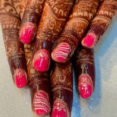 For the bride who loves a pop of color. This set features bright pink nails with silver glitter accents and intricate white swirl patterns, designed to stand out alongside traditional mehendi.