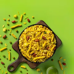 A top-down shot of Navratan Mixture for Sartaj Sweets & Namkeen. The vibrant green background and scattered ingredients create a dynamic, eye-catching image designed for modern snack packaging and e-commerce listings.